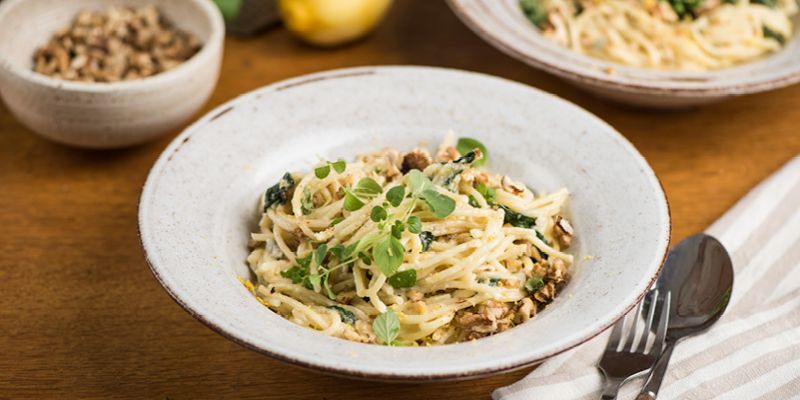 Pasta mit Spinat und Gorgonzolasauce angerichtet in einem tiefen Teller.