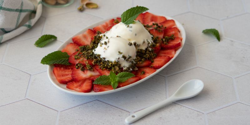 Auf einem Teller angerichtetes Erdbeer-Carpaccio mit süßem Pistazien-Pesto und Vanilleeis