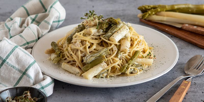 Auf einem Teller angerichtete Spaghetti mit grünem und weißem Spargel